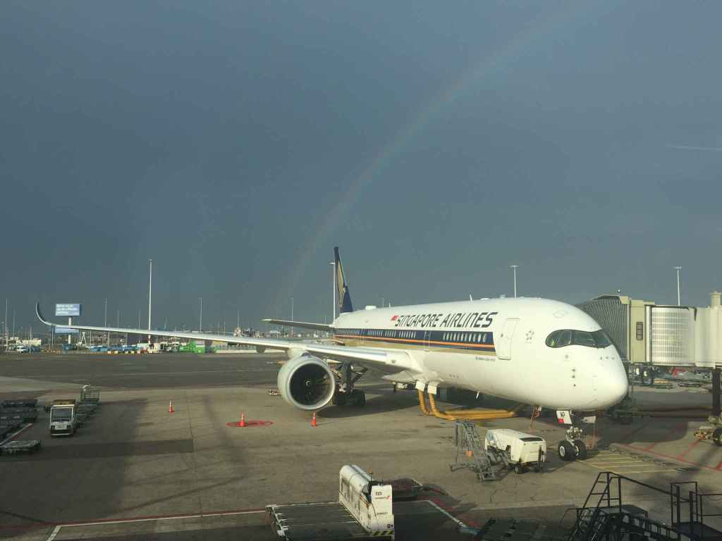 Make a wish! Singapore Airlines Airbus A350 framed with a rainbow at Amsterdam Schiphol airport as seen from the boarding gate windows.