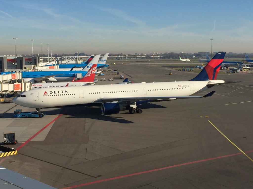 A Delta A330 pushes back off the gate at Amsterdam Schiphol airport as viewed from the magnificent open air observation deck.